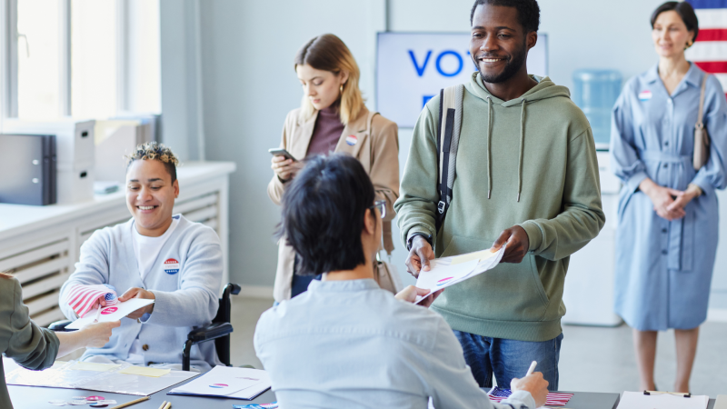 person handing a poll worker their ballot