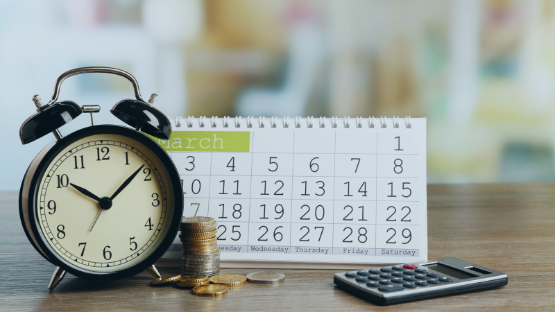 clock with calculator and change with a calendar in the background
