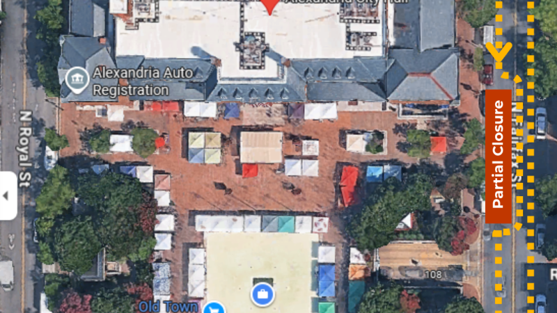 Aerial view of the Alexandria City Hall and surrounding area. The image shows the Old Town Farmers Market with numerous vendor tents set up. Streets around the market include Cameron St, N Royal St, and King St. North Fairfax Sts is marked on the right side indicating "Partial Closure." Dashed yellow arrows pointing northbound and southbound on N Fairfax St show the flow of traffic around the southbound partial closure.