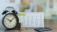 clock with calculator and change with a calendar in the background