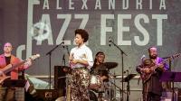 band on stage playing instruments with banner that says alexandria jazz fest behind them on stage